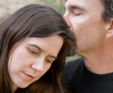 72a_Family_Couple3_TRes A man kissing the top of his wife's head to console her after their child moved out