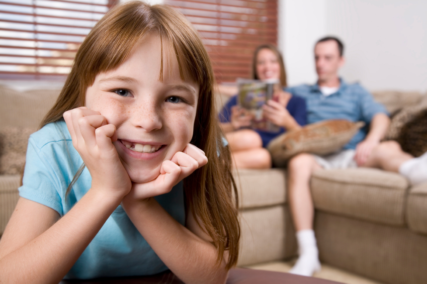 young girl watching tv in family room with her parents