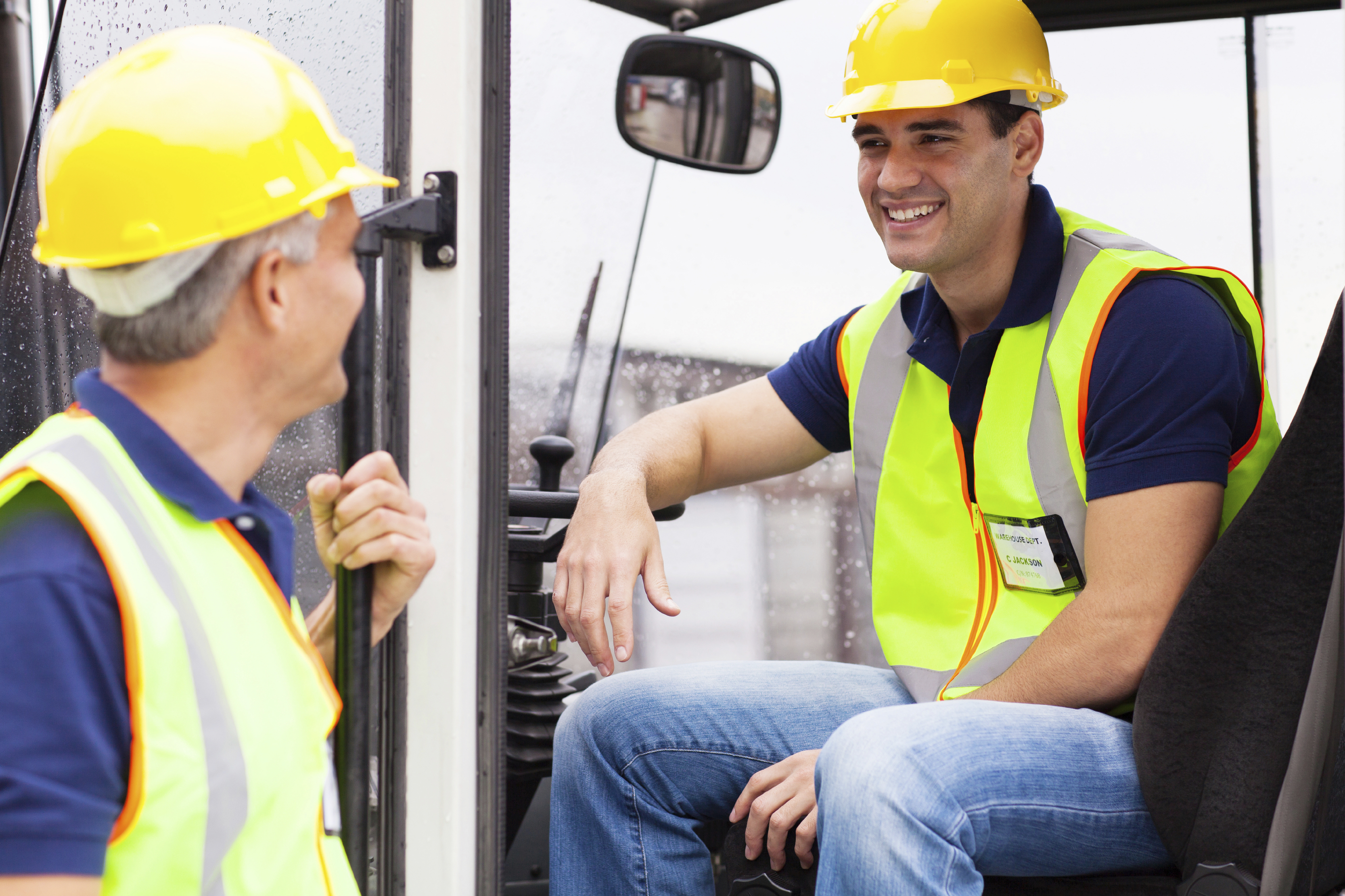 Warehouse co-workers chatting during break on forklift