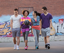 Friends are walking together and one friend is holding basketball Friends are walking together and one friend is holding basketball